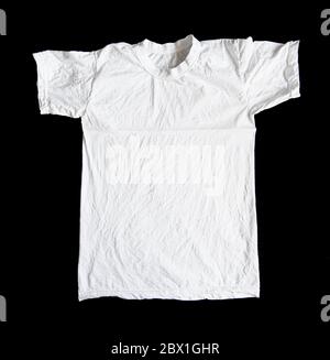 White crumpled t-shirt isolated on black background. Wrinkled shirt, top view. Stock Photo