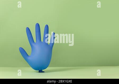 Latex inflated rubber glove inflated like balloons on a green background with copy space. Covid-19, stay at home Stock Photo