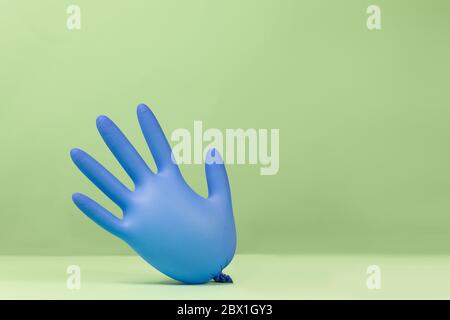 Latex inflated rubber glove inflated like balloons on a green background. Funny colorful and bright concept Stock Photo