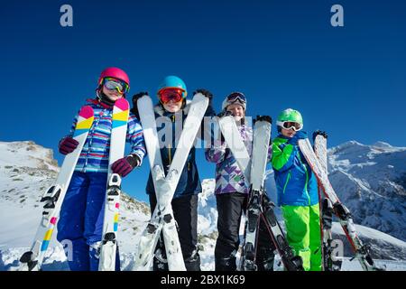 Ski vacation portrait many children stand with sport equipment in hands lean to camera wearing color google and helmets Stock Photo