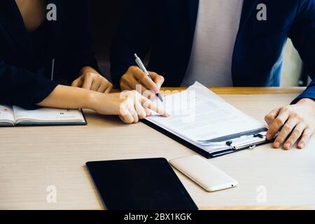 Businessman and businesswoman signing paper (insurance, contract, important) Stock Photo