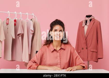 Portrait of young woman with curly hair sitting at the table and smiling she consulting about stylish clothes Stock Photo