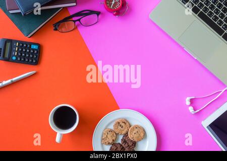 Laptop, office supplies, coffee and cookies on colorful background. Free space for text Stock Photo