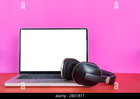 Modern laptop with blank screen and headphones on colorful background. Stock Photo