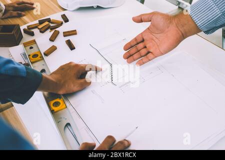 Team of engineers discussing architecture plan sketch at the construction site. Stock Photo
