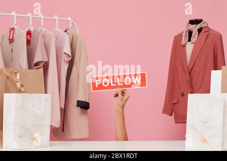 Image of female hand holding placard and say to follow her clothes shop Stock Photo