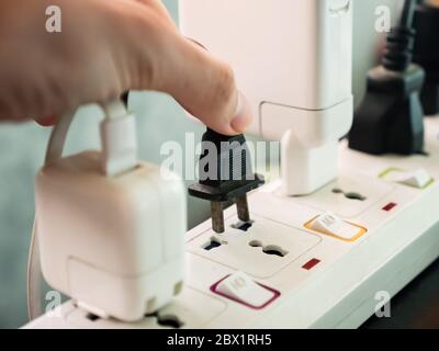 Hand holding electric plug, Multiple socket with connected plugs. Stock Photo