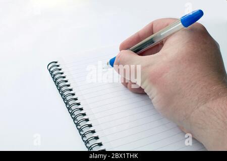 Male hand close up writing with a ball point pen on a notepad on a white background Stock Photo