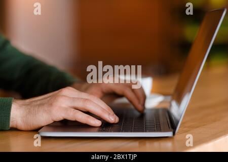 Freelancer hands typing on laptop keyboard, cafe interior Stock Photo
