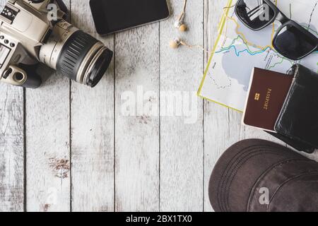 Top view of Camera with cap,sunglasses,wallet,smart phone,map and passport on white wooden table background, Travel concept Stock Photo