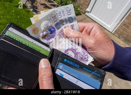 Close up of man person taking hand hands paying £20 twenty pound pounds notes cash money from out of wallet England UK United Kingdom Great Britain Stock Photo