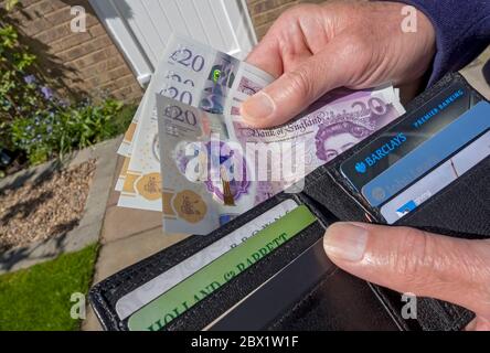 Close up of man person taking paying English £20 twenty pound notes cash money from out of wallet England UK United Kingdom GB Great Britain Stock Photo