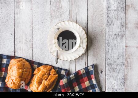 Top view of Coffee cup with bread and tablecloth on wooden table background Stock Photo