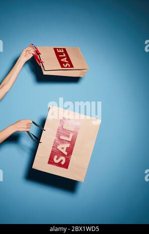 Close-up of woman holding shopping paper bags isolated on blue background she doing shopping on sale Stock Photo
