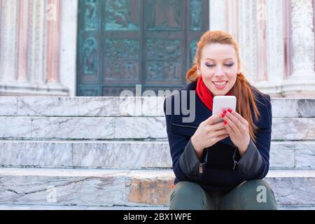 Happy ginger woman girl sitting on the floor and showing something over ...