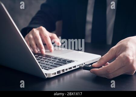 Close up of Businessman using flash drive connect to laptop on the office desk. Stock Photo