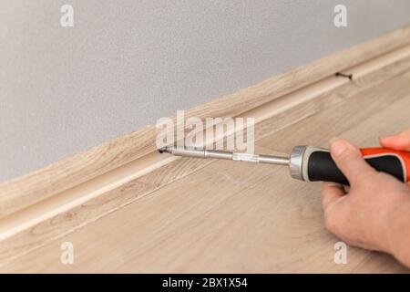 Man work on the installation of plastic plinth on grey wall. Close up. Stock Photo