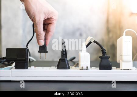 Hand holding electric plug, Multiple socket with connected plugs. Stock Photo