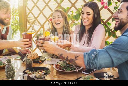 Happy friends lunching healthy food and drinking smoothies fresh fruits - Young people having fun eating in coffee brunch vintage bar Stock Photo