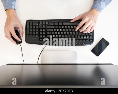 Top view of male hands working on computer on the desk. Stock Photo