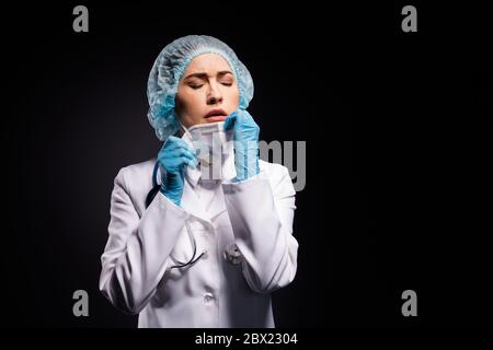 Photo of tired exhausted lady doc hold arms taking off protective mask after last late operation breathing fresh air wear gloves lab white coat Stock Photo