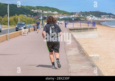 A young man jogging along a beach promenade during the coronvirus pandemic Stock Photo