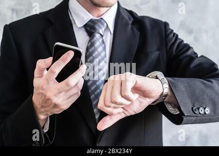 Close up of businessman using smart phone and checking time on his wrist watch. Stock Photo