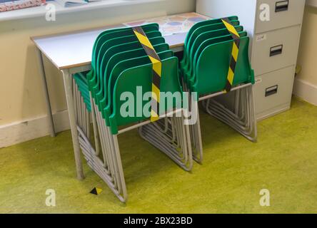 Social distancing measures in a school classroom with tape separating tables and chairs in response to the COVID-19 Coronavirus. Stock Photo