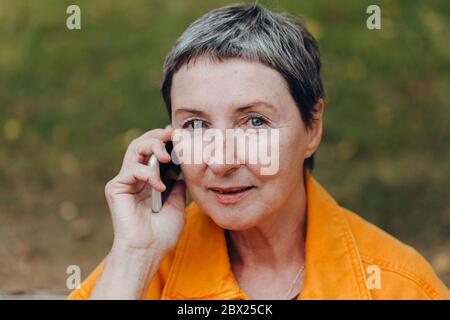 Happy senior woman on the city streets using cellphone. Stock Photo