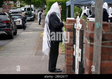 Manchester, UK. 4th June, 2020. Orthodox Jewish men conduct their morning prayers in adjacent gardens in Salford so as to comply with new rules allowing 6 people to congregate in one garden but still achieve a minyan, a quorum of ten Jewish adults required for certain religious obligations, Manchester, UK. Credit: Jon Super/Alamy Live News. Stock Photo