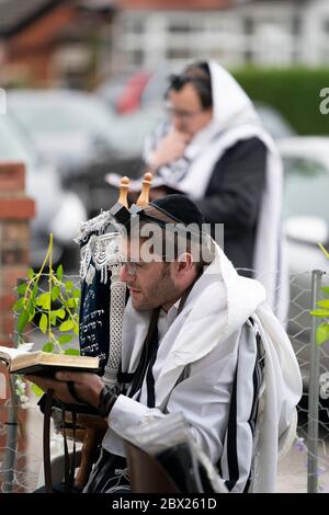 Manchester, UK. 4th June, 2020. Orthodox Jewish men conduct their morning prayers in adjacent gardens in Salford so as to comply with new rules allowing 6 people to congregate in one garden but still achieve a minyan, a quorum of ten Jewish adults required for certain religious obligations, Manchester, UK. Credit: Jon Super/Alamy Live News. Stock Photo