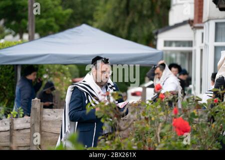 Manchester, UK. 4th June, 2020. Orthodox Jewish men conduct their morning prayers in adjacent gardens in Salford so as to comply with new rules allowing 6 people to congregate in one garden but still achieve a minyan, a quorum of ten Jewish adults required for certain religious obligations, Manchester, UK. Credit: Jon Super/Alamy Live News. Stock Photo