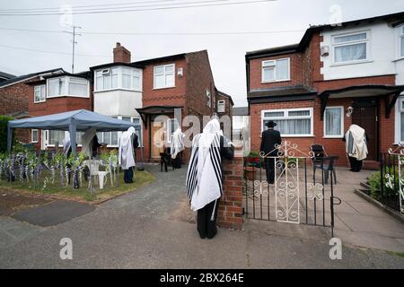 Manchester, UK. 4th June, 2020. Orthodox Jewish men conduct their morning prayers in adjacent gardens in Salford so as to comply with new rules allowing 6 people to congregate in one garden but still achieve a minyan, a quorum of ten Jewish adults required for certain religious obligations, Manchester, UK. Credit: Jon Super/Alamy Live News. Stock Photo