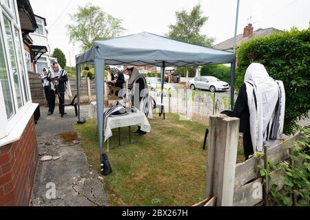 Manchester, UK. 4th June, 2020. Orthodox Jewish men conduct their morning prayers in adjacent gardens in Salford so as to comply with new rules allowing 6 people to congregate in one garden but still achieve a minyan, a quorum of ten Jewish adults required for certain religious obligations, Manchester, UK. Credit: Jon Super/Alamy Live News. Stock Photo