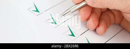 Male businessman hand hold silver pen and make green check mark closeup Stock Photo