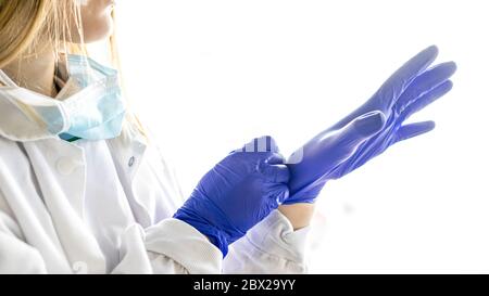Medicine and Surgery theme: female nurse putting on protective blue gloves Stock Photo