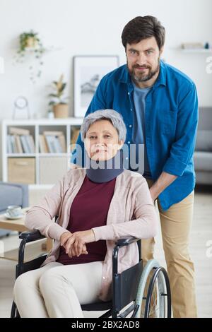 Portrait of mature bearded man caring about disabled senior woman in wheelchair at home Stock Photo