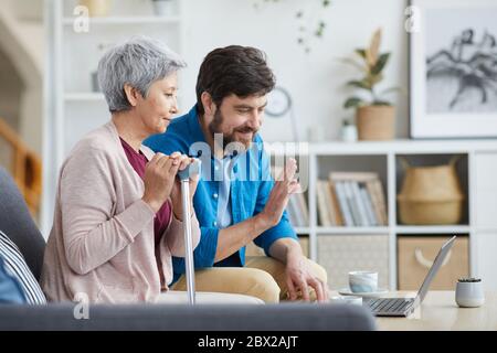 Mature man and senior woman sitting on sofa and talking online using laptop computer at home Stock Photo