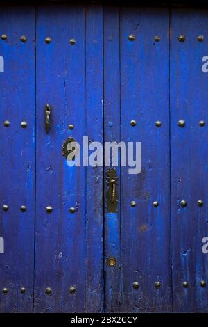 Old rustic wooden door with different layers of cracked dark blue paint Stock Photo