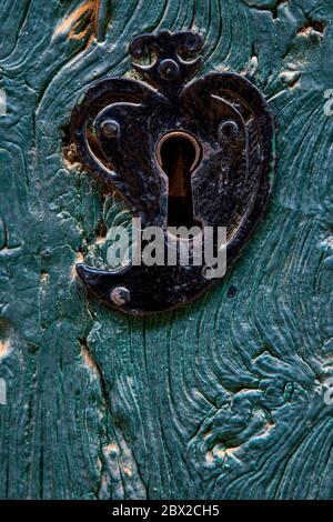Old heart shaped door lock on a textured wooden door painted in blue Stock Photo