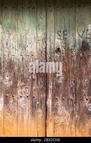 Old rustic wooden door with different layers of cracked paint in green, brown and orange colors Stock Photo