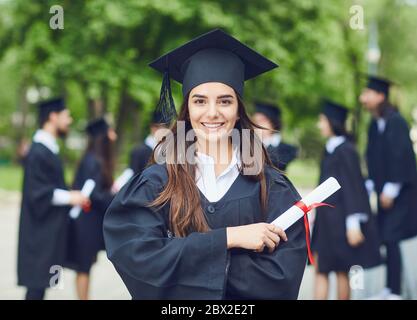 A young female graduate against the background of university graduates. Stock Photo