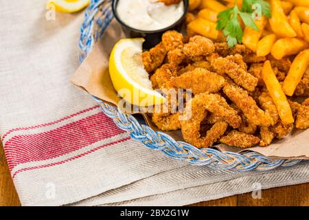 Crispy Breaded Clam Strips Snack Size. Deep Fried Breaded Clams Fingers and French Fried Potatoes with Tartar Dipping Sauce Stock Photo