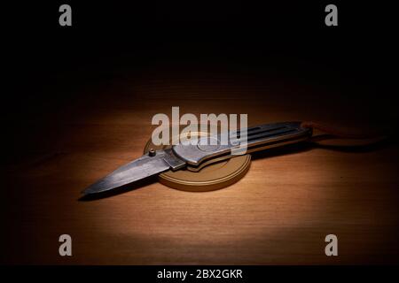 Silver jackknife on a wood table with a top light Stock Photo