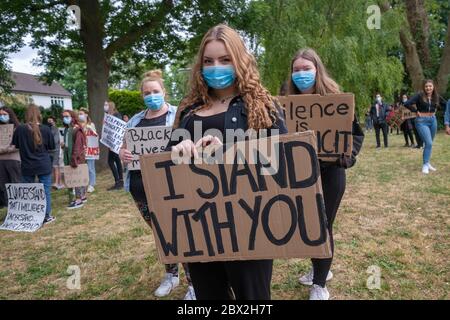 Staines, Surrey, UK. 4th June 2020. Several hundred young local residents march around Staines from the council offices with placards and shouting 'Black Lives Matter' and 'I can't Breathe' in protest against the death of George Floyd and others who have died at the hands of police in the USA and here in the UK. They 'took the knee' at the side of the old Town Hall before marching down the High St into the Two Rivers shopping park where they staged a silent die-in for 8 minutes 46 seconds, the time Floyd was restrained by a police officer. Peter Marshall/Alamy Live News Stock Photo