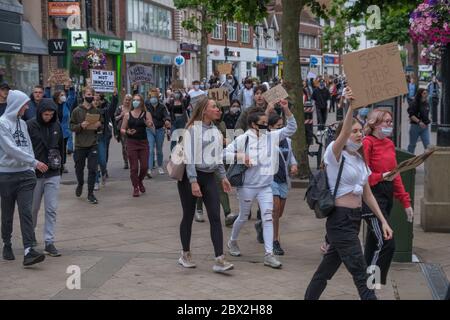 Staines, Surrey, UK. 4th June 2020. Several hundred young local residents march around Staines from the council offices with placards and shouting 'Black Lives Matter' and 'I can't Breathe' in protest against the death of George Floyd and others who have died at the hands of police in the USA and here in the UK. They 'took the knee' at the side of the old Town Hall before marching down the High St into the Two Rivers shopping park where they staged a silent die-in for 8 minutes 46 seconds, the time Floyd was restrained by a police officer. Peter Marshall/Alamy Live News Stock Photo