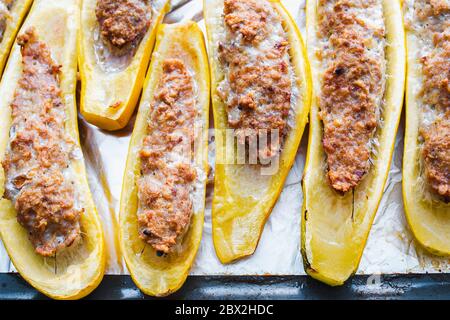 Sliced zucchini filled with minced meat on a baking sheet Stock Photo