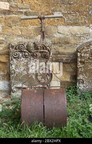 Vintage earth roller in a graveyard, stone headstones leaning against church Stock Photo