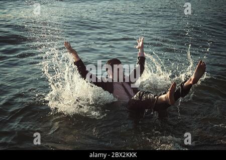Young man swimming with business suit in the sea. Tired of work Stock Photo