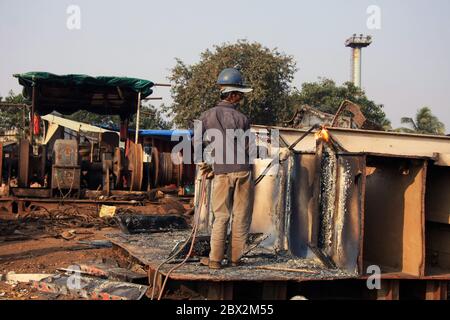 Shipbreaking Yard in Darukhana, Mumbai, India – INS Vikrant dismantling with scrap metal & workers in background Stock Photo